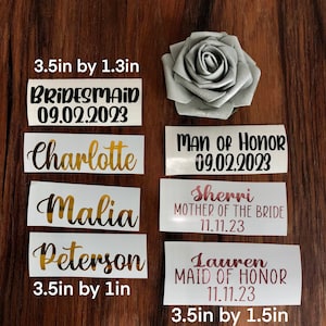 Peut inclure: Ensemble de d&eacute;calcomanies en vinyle personnalis&eacute;es pour les f&ecirc;tes de mariage. Comprend des noms, des titres et des dates, tels que "Bridesmaid 09.02.2023" et "Man of Honor 09.02.2023". Les d&eacute;calcomanies mesurent 8,9 cm de long et 2,5 &agrave; 3,8 cm de large. Une rose argent&eacute;e est &eacute;galement pr&eacute;sente.
