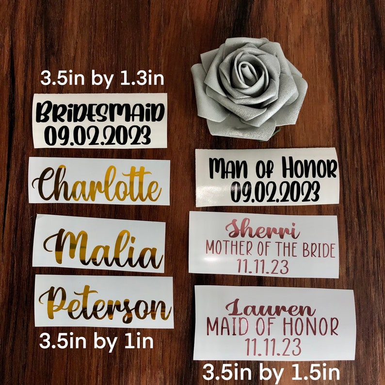 Peut inclure: Ensemble de d&eacute;calcomanies en vinyle personnalis&eacute;es pour les f&ecirc;tes de mariage. Comprend des noms, des titres et des dates, tels que "Bridesmaid 09.02.2023" et "Man of Honor 09.02.2023". Les d&eacute;calcomanies mesurent 8,9 cm de long et 2,5 &agrave; 3,8 cm de large. Une rose argent&eacute;e est &eacute;galement pr&eacute;sente.