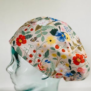 May include: A pink scrub hat with a floral print featuring strawberries, flowers, and butterflies.