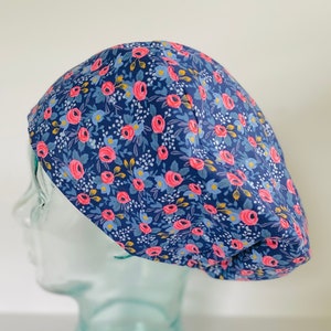 May include: A blue and pink floral print surgical scrub hat. The hat is made of a soft, comfortable fabric and is designed to be worn by medical professionals.