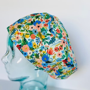 May include: A light blue scrub hat with a floral print featuring pink, yellow, blue, and green flowers.