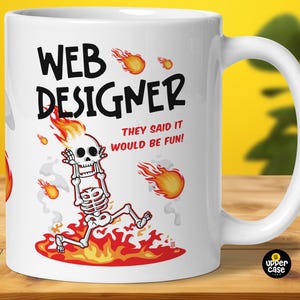 May include: White ceramic mug with a black and red graphic of a skeleton in flames. The text "WEB DESIGNER" is above the skeleton and the text "THEY SAID IT WOULD BE FUN!" is below the skeleton.