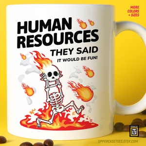 May include: White ceramic mug with a black and red illustration of a skeleton on fire. The text "HUMAN RESOURCES THEY SAID IT WOULD BE FUN!" is printed on the mug.