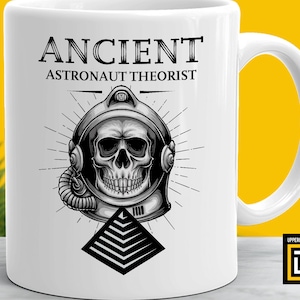 May include: White ceramic mug with a black and white illustration of a skull wearing an astronaut helmet. The text "ANCIENT ASTRONAUT THEORIST" is printed above the illustration. The mug has a black handle.