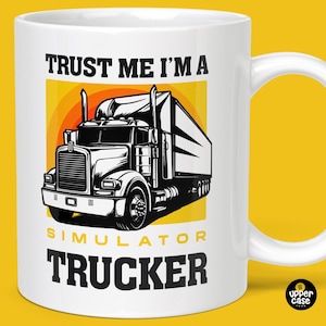 Può includere: Una tazza in ceramica bianca con un'illustrazione in bianco e nero di un camion. Il testo "Trust me I'm a Simulator Trucker" è stampato sulla tazza in nero.