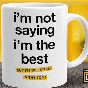 Puede incluir: Taza de cerámica blanca con texto negro que dice "i'm not saying i'm the best BUT I'M DEFINITELY IN THE TOP 1".
