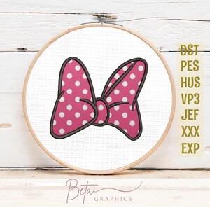Può includere: Un telaio da ricamo circolare in legno contenente tessuto bianco con un fiocco rosa ricamato a macchina, caratterizzato da pois bianchi e un contorno scuro. A destra, il testo DST, PES, HUS, VP3, JEF, XXX, EXP è stampato in oro.