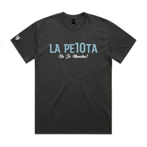 Puede incluir: Camiseta gris oscuro con el texto "LA PELOTA" en azul claro, sobre el texto "No Se Mancha!" en letra cursiva. Un peque&ntilde;o logotipo es visible en la manga izquierda. Es una prenda de vestir informal.