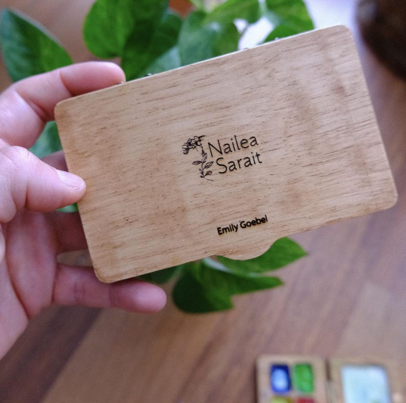 Puede incluir: Una caja de madera con un dise&ntilde;o floral y el texto "Nailea Sarai" y "Emily Goebel" grabado en la tapa.