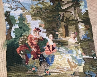May include: A vintage needlepoint tapestry depicting three figures in a garden setting. The figures are dressed in 18th-century clothing and are surrounded by lush greenery and flowers. The tapestry is framed with a beige canvas and has the text "L'Innocence" in the bottom right corner.