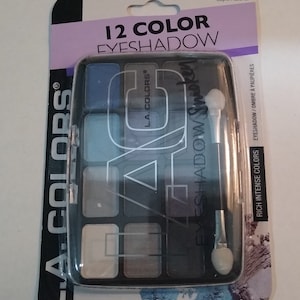 May include: A 12-color eyeshadow palette with a black and silver design. The palette includes a small applicator brush and the text "L.A. Colors® Eyeshadow Smokey" on the front. The palette weighs 0.49 oz (14g).