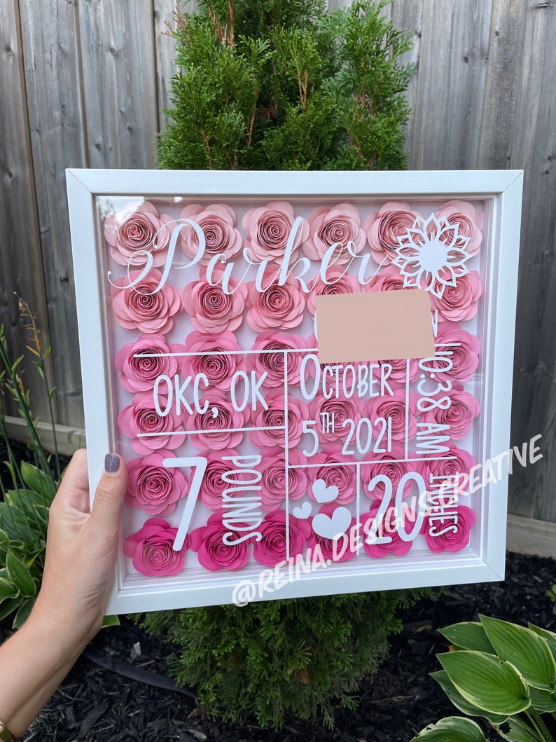 May include: A white frame with a pink and white floral design. The frame includes the name "Parker", the date "October 5th 2021", the location "OKC, OK", the weight "7 pounds", and the length "20 inches".