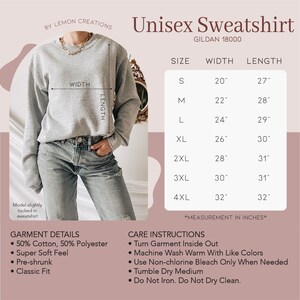 Puede incluir: Una sudadera gris unisex con el texto "Unisex Sweatshirt" y "GILDAN 18000" impreso en ella. La sudadera se muestra en una modelo que lleva jeans azules. Se incluye una tabla de tallas con medidas en pulgadas para las tallas S a 4XL.