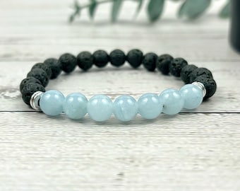 May include: A bracelet made of black lava rock beads and light blue aquamarine beads. The bracelet has a silver clasp.