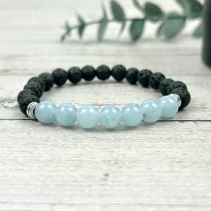 May include: A bracelet made of black lava rock beads and light blue aquamarine beads. The bracelet has a silver clasp.