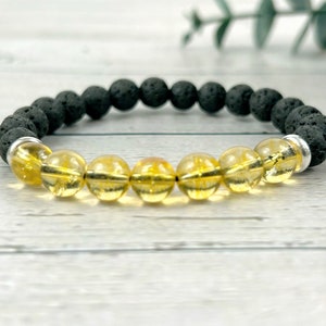 May include: A bracelet made with black lava rock beads and yellow citrine beads. The bracelet has a silver spacer bead.