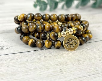 May include: A multi-strand bracelet made of tiger's eye beads with a gold-toned lotus flower charm.