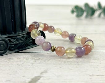 May include: A multi-colored gemstone bracelet with beads of amethyst, rose quartz, and citrine. The bracelet is made with natural stones and has a simple design.