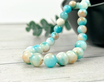 May include: A strand of blue and white marbled round beads. The beads are strung on a clear thread and are arranged in a circular pattern.