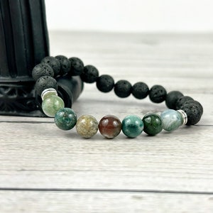 May include: A black lava rock bracelet with green, brown, and white agate beads.