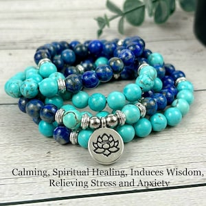 May include: A layered mala bracelet with turquoise and lapis lazuli beads. The bracelet has a silver charm with a lotus flower design. The text "Calming, Spiritual Healing, Induces Wisdom, Relieving Stress and Anxiety" is below the bracelet.