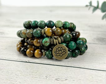 May include: A multi-strand bracelet with green and brown beads, featuring a lotus flower charm. The bracelet is made of natural stones and is perfect for layering.