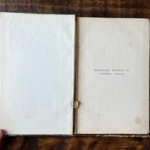 May include: An open book with a white cover and black text that reads "Missionary Travels in Central Africa".