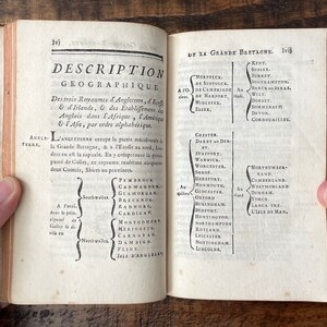 May include: An open book with a black and white text on a white background. The text is in French and describes the geography of England, Ireland, Scotland, Africa, America, and Asia. The book is open to pages 1vj and 1vij.
