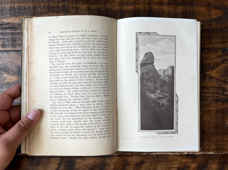 May include: A black and white photograph of a rocky mountain range. The image is from a book titled "Missionary Travels by E.G. Arnot". The caption below the image reads "The Black Rocks of Puma Ngoho."