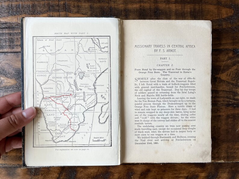 May include: An open book with a map of Africa and text about missionary travels in Central Africa by P.S. Arnot. The map shows the route from Natal to Kama's Country.