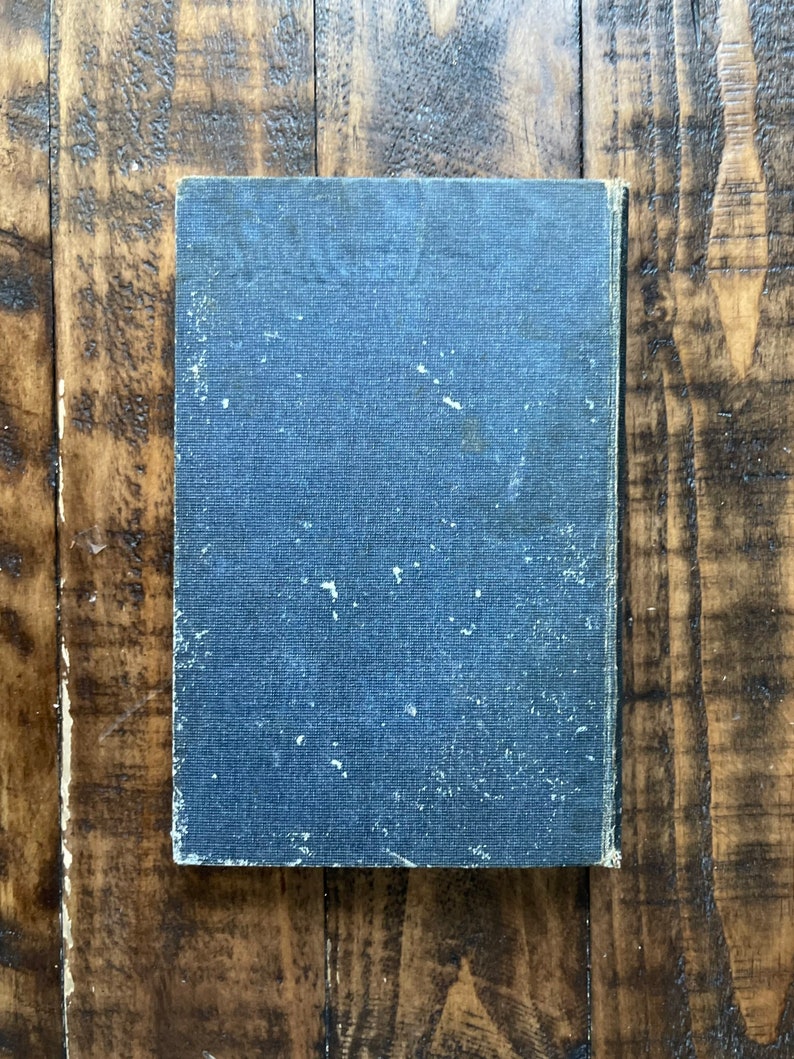 May include: A dark blue hardcover book with a textured cover. The book is slightly worn and has a few white spots on the cover.