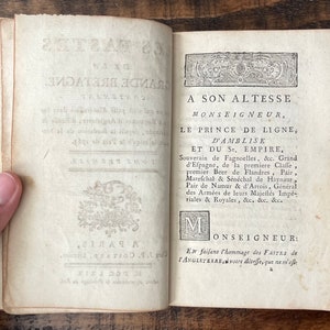 May include: An antique book with a title page dedicated to Prince de Ligne, D'Amblise, and the Holy Roman Empire. The text is in French and includes his titles and roles.
