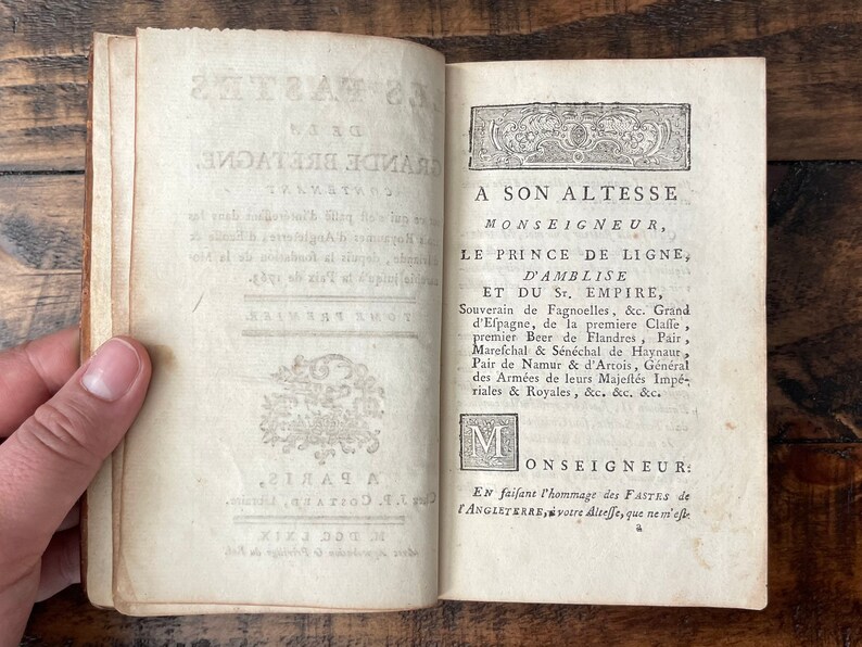 May include: An antique book with a title page dedicated to Prince de Ligne, D'Amblise, and the Holy Roman Empire. The text is in French and includes his titles and roles.