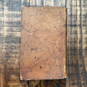 May include: A worn, brown leather-bound book with a slightly faded appearance.