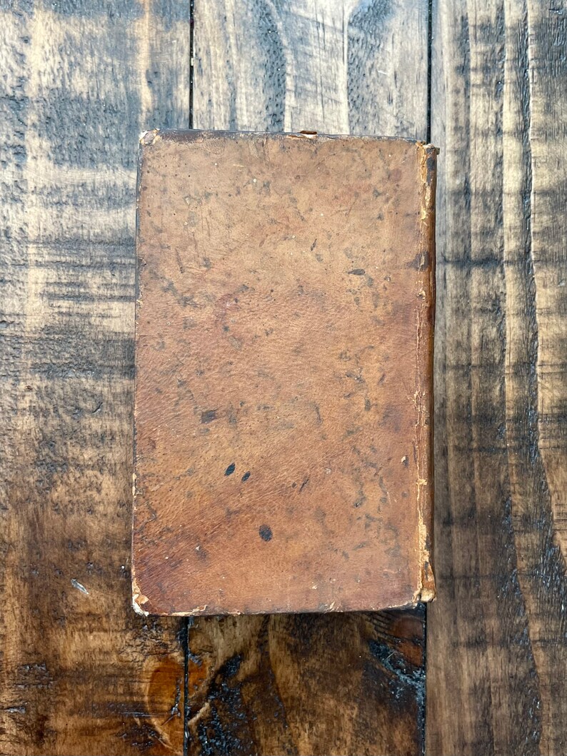 May include: A worn, brown leather-bound book with a slightly faded appearance.