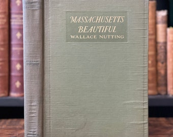 May include: A green hardcover book titled "Massachusetts Beautiful" by Wallace Nutting. The book is on a wooden surface.
