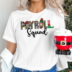 Peut inclure: T-shirt blanc avec un motif de Noël qui dit "Payroll Squad". Le motif représente un bonhomme de neige, un renne et un lutin de Noël.