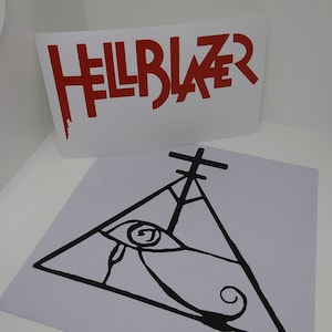 May include: Two white rectangular stickers. The top sticker has the word "HELLBLAZER" in red, stylized lettering. The bottom sticker features a black line drawing of an eye within a triangle, with a cross above.
