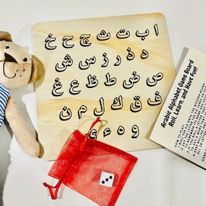 Peut inclure: Un plateau de jeu en bois avec des lettres de l'alphabet arabe imprimées dessus. Un sac à cordon rouge avec un dé blanc se trouve au premier plan. Le plateau de jeu est intitulé "Arabic Alphabet Game Board Roll, Learn, and Have Fun!" avec des instructions sur la façon de jouer.