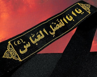 Könnte beinhalten: Schwarzes Stoffband mit goldener arabischer Schriftstickerei und dekorativen Bordüren. Der Text ist mittig auf dem Band platziert, mit einem stilisierten Design an jedem Ende. Der Hintergrund ist ein Farbverlauf von Rot und Orange.