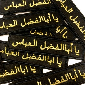 Peut inclure: Plusieurs écussons rectangulaires noirs avec des inscriptions arabes brodées en or. Les écussons sont disposés de manière dense, avec le texte "Ya Aba Al Fadl Al Abbas" visible sur plusieurs. La broderie a une texture en relief.