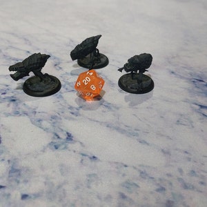 May include: Four miniature grey spaceships on black bases surrounding an orange twenty-sided die with white numbers.