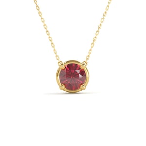 May include: A gold necklace featuring a round, faceted, deep red gemstone pendant. The pendant is set in a gold bezel with four prongs. The chain is a delicate gold link. The jewelry is displayed against a white background.