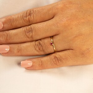 Peut inclure: Une d&eacute;licate bague en or avec une petite pierre pr&eacute;cieuse rouge en forme de c&oelig;ur.