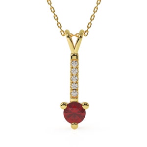 Puede incluir: Un collar de oro con un colgante de piedra roja y peque&ntilde;as piedras transparentes. El colgante est&aacute; en una cadena de oro delicada.