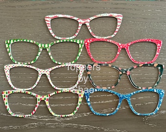 May include: Six pairs of Christmas-themed glasses with different patterns. The glasses are all white with red, green, and blue accents. The patterns include snowflakes, candy canes, and Christmas trees.