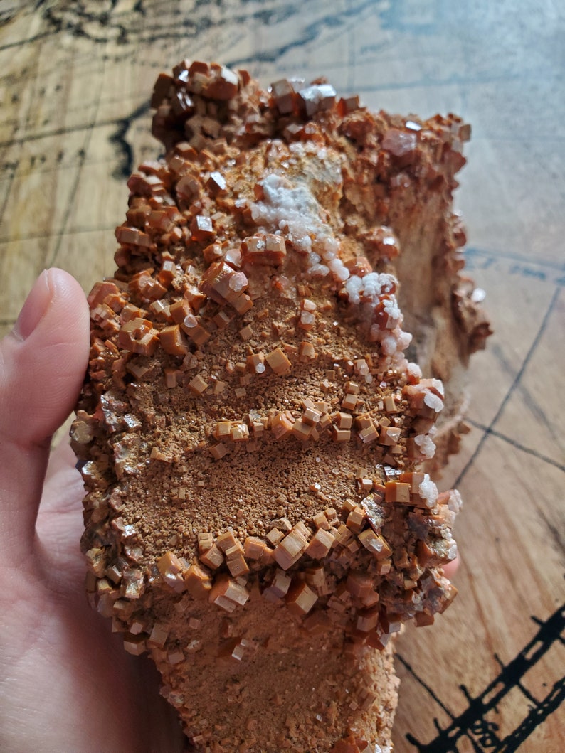 May include: A cluster of orange-brown crystals with a rough, textured surface. The crystals are arranged in a layered pattern, creating a unique and interesting visual.