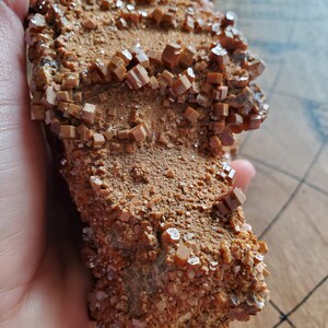 May include: A large, rough, brown rock covered in small, orange, sparkly crystals.