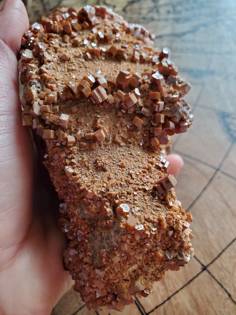 May include: A large, rough, brown rock covered in small, orange, sparkly crystals.