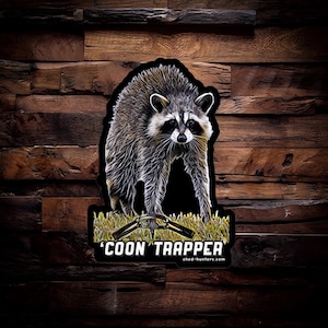 May include: A black and white sticker with a raccoon illustration and the text "'COON TRAPPER' shed-hunters.com".